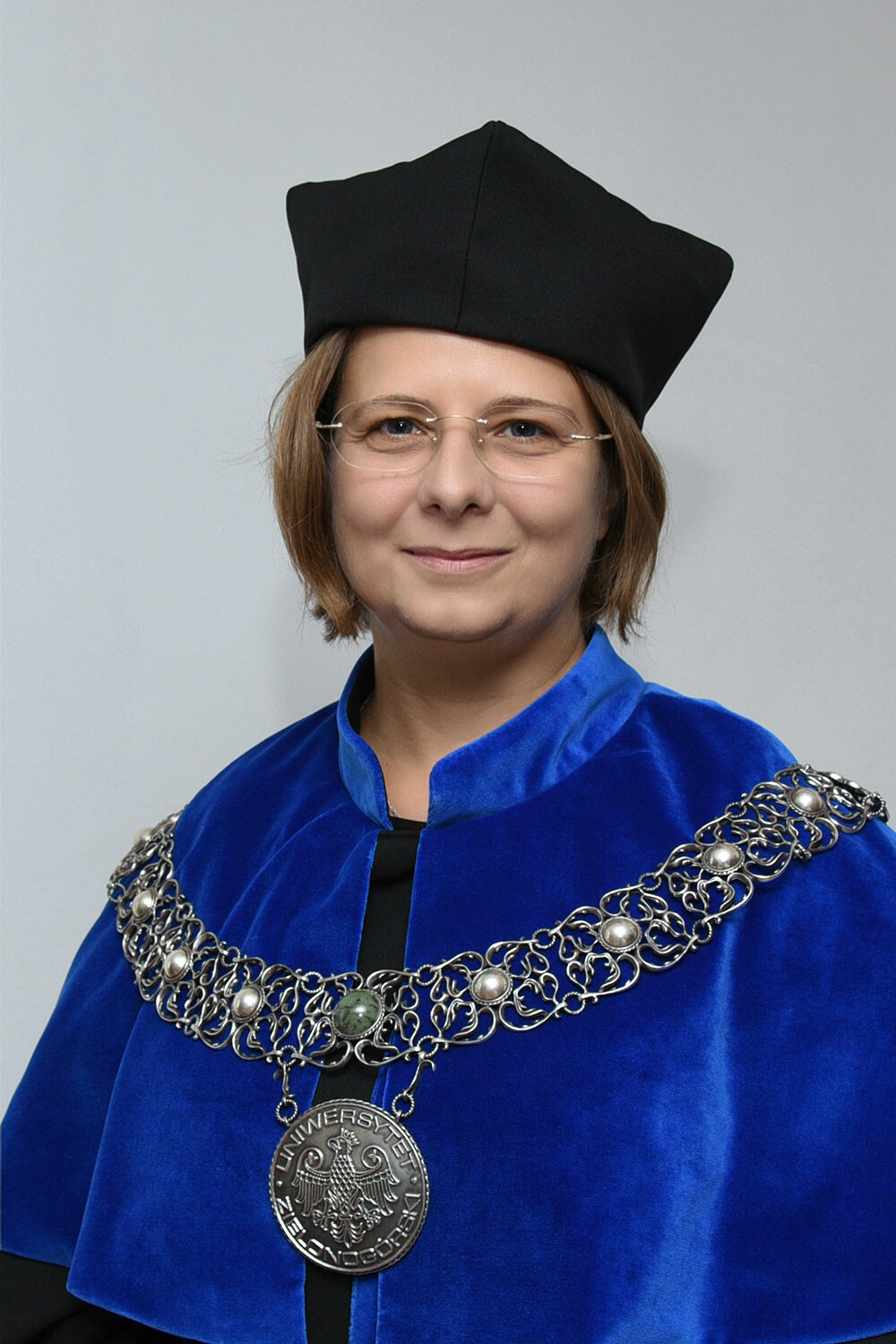 Zdjęcie Dziekan Wydziału Lekarskiego i Nauk o Zdrowiu UZ dr hab. n. med. Agnieszka Ziółkowska, prof. UZ W stroju reprezentacyjnym, występuje chabrowym płaszczu (todze) oraz ozdobnym łańcuchem z symbolami Uniwersytetu Zielonogórskiego.